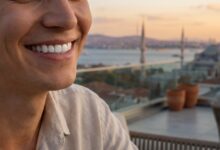 A close-up, photorealistic image focused on a person's perfect, white teeth and joyful smile, with the sunny, blurred skyline of Istanbul, Turkey, visible in the background, representing a successful dental tourism trip.