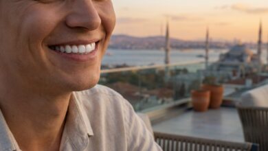 A close-up, photorealistic image focused on a person's perfect, white teeth and joyful smile, with the sunny, blurred skyline of Istanbul, Turkey, visible in the background, representing a successful dental tourism trip.