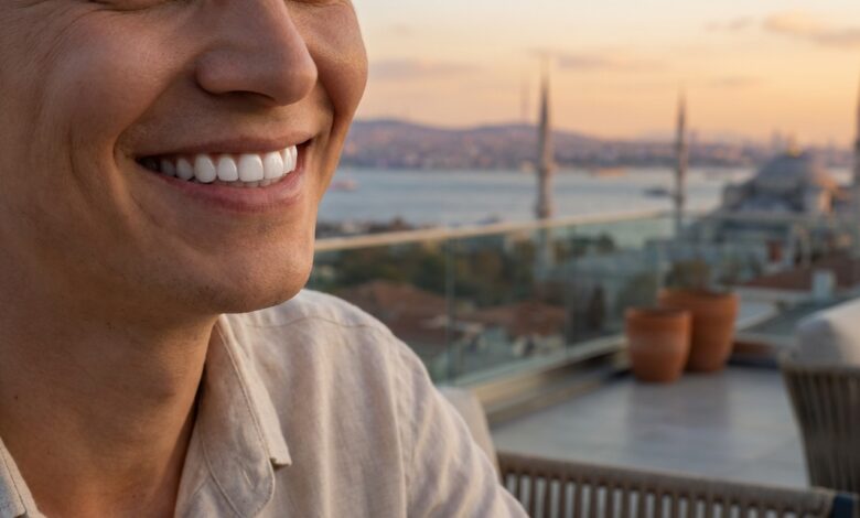 A close-up, photorealistic image focused on a person's perfect, white teeth and joyful smile, with the sunny, blurred skyline of Istanbul, Turkey, visible in the background, representing a successful dental tourism trip.