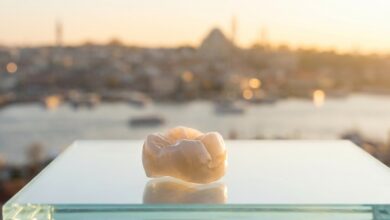 A photorealistic close-up of a flawless Zirconia dental crown on a clean surface, with the blurred skyline of Istanbul, Turkey in the background during a warm sunrise, symbolizing high-quality dental tourism.