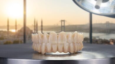 A photorealistic image of a full-arch Zirconia dental implant bridge on a clean surface in a modern dental clinic, with a blurred view of Istanbul, Turkey, visible through a window in the background.