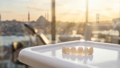 A photorealistic close-up of perfectly crafted dental veneers on a clean surface. In the background, the Istanbul, Turkey skyline is beautifully blurred out of focus through a window during a warm sunset, representing dental tourism.