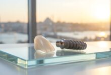A photorealistic close-up of a high-quality dental implant and a porcelain veneer on a sterile surface, with the iconic Istanbul skyline softly blurred in the background through a window at sunrise.