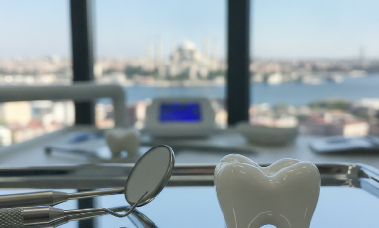 A close-up of a pristine, white ceramic dental crown on a sterile surface with blurred dental tools. In the background, a softly focused cityscape of Istanbul, Turkey, under a clear sky.