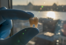 Close-up of a meticulously crafted, natural-looking dental crown held by a gloved hand, symbolizing quality dental care. In the softly blurred background, a sunlit cityscape of Turkey is visible, suggesting medical tourism and the location.