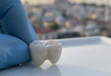 A brilliant white, perfectly crafted ceramic dental crown in sharp focus, with a very softly blurred background showing the architectural silhouette of Istanbul, Turkey.