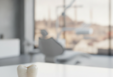 A photorealistic close-up of a pristine, white ceramic dental crown, perfectly shaped and detailed, sitting on a clean, light surface. The background is softly blurred, showing hints of a modern dental clinic environment and a distant, indistinct Turkish city skyline through a window.