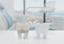 Close-up of two perfect, luminous dental crowns on a reflective surface, one appearing translucent and the other solid white, set against a softly blurred background hinting at a modern dental clinic and a distant Turkish cityscape.