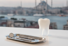 A close-up, photorealistic image of a modern dental instrument tray or a conceptual model of a bright white tooth, symbolizing advanced dental crowns, in a pristine clinic setting. The background is softly blurred, revealing the iconic silhouette of Istanbul, Turkey, with its historical mosque domes and minarets or a Bosphorus view, suggesting dental tourism. The lighting is bright and cinematic, with a shallow depth of field. No visible text.