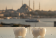 A gleaming, perfectly shaped white dental crown prominently displayed in the foreground, with the iconic, blurred skyline of Istanbul, Turkey, featuring domes and minarets, in the soft-focus background.